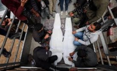 فلسطينيون بجوار جثماني شخصين استشهدا في غارة إسرائيلية 